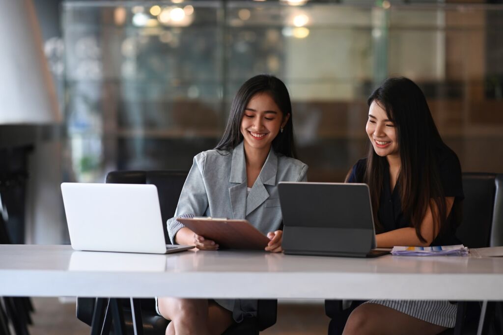 Two businesswoman working on tablet computer and discussing business data at modern office.