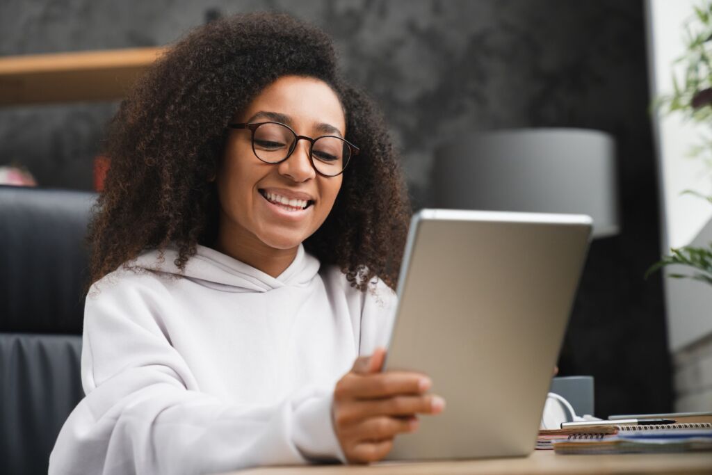 Schoolgirl using digital tablet at home, doing homework assignment online, browsing social media